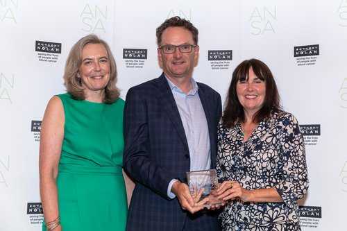 photo of three people holding an award